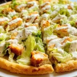 Sliced Chicken Crust Caesar Salad Pizza served on a white plate