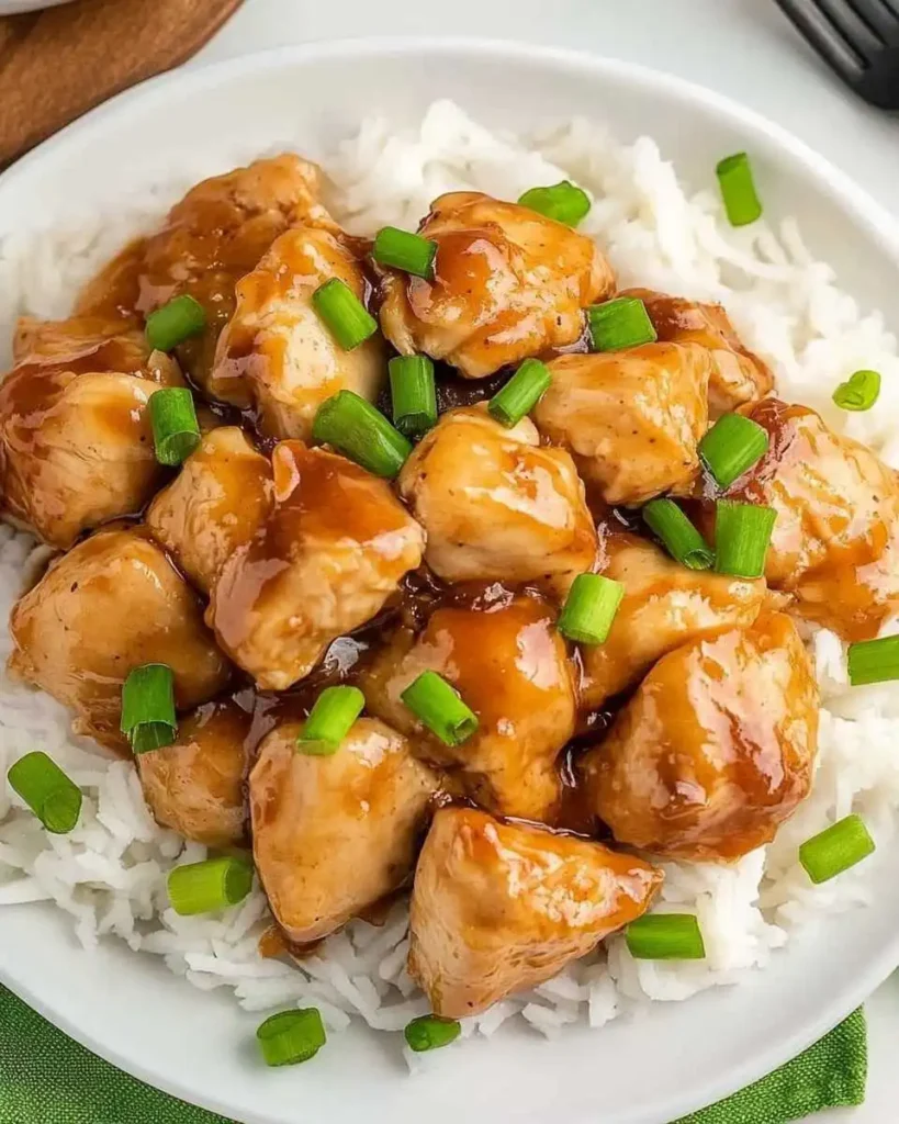 Sweet Hawaiian Crockpot Chicken served over white rice, topped with a savory glaze and fresh green onions.